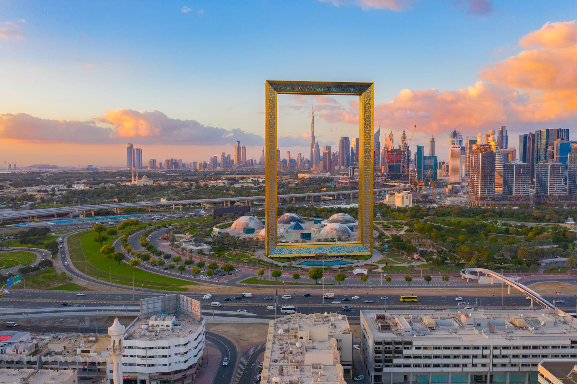 Aerial view of the Dubai Frame in Zabeel Park at sunset, with the Downtown Dubai skyline and Burj Khalifa behind
